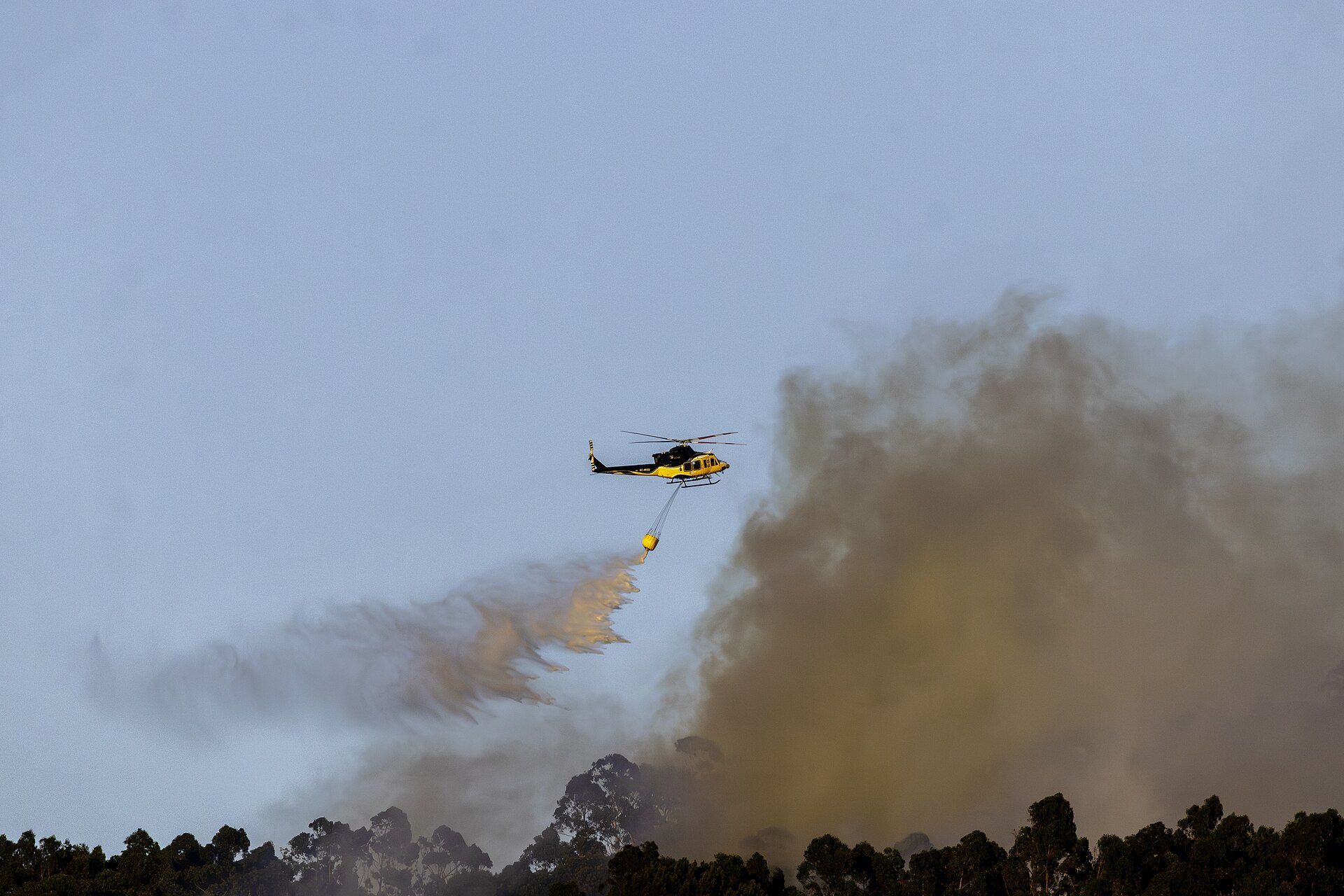 Un helicóptero Bell 412 fumigando el fuego entre Pontevedra y Marín.